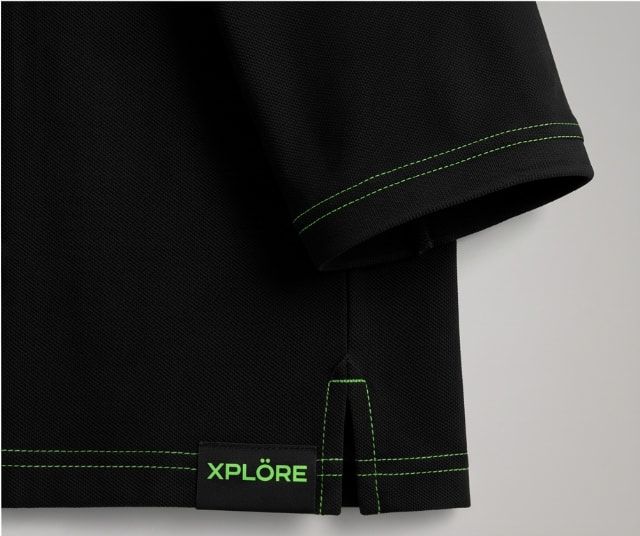 Detalle del bajo y etiqueta del polo XPLÖRE