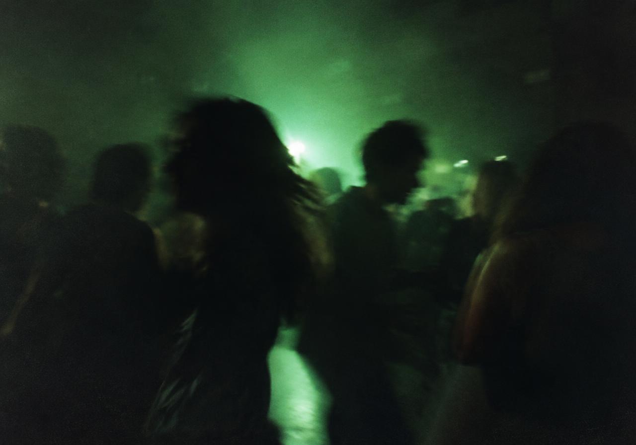 Personas bailando juntas en una pista iluminada en verde
